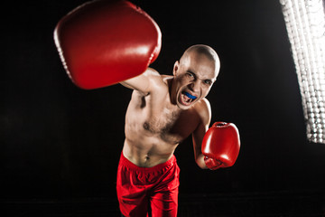 The young man kickboxing on black  with kapa in mouth