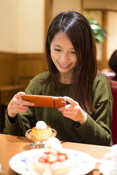 Woman take the photo on her food at coffee shop
