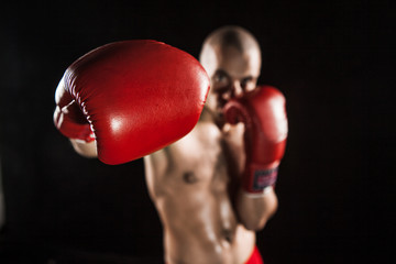 The young man kickboxing on black