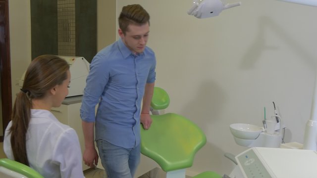 Patient Enters to a Room in Shoe Covers Sits Down on Chair Dentist Young Woman is Sitting Smiling Talking to a Client Dental Clinic Visit to the Dentist