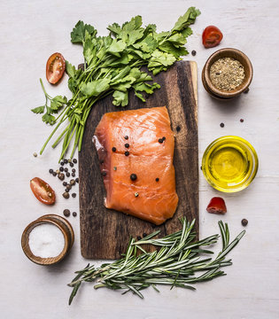 ece of smoked salmon on a cutting board with herbs and spices on wooden rustic background top view