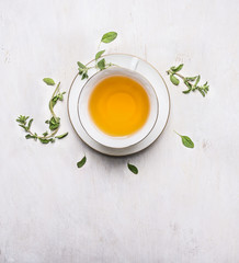 tea with thyme in a white cup on a white saucer place for text  on wooden rustic background top view