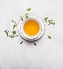 Crédence de cuisine en verre imprimé Theé tea with thyme in a white cup on a white saucer place for text  on wooden rustic background top view
