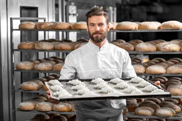 Fotobehang Handsome baker in uniform holding tray full of freshly baked croissants at the manufacturing © rh2010