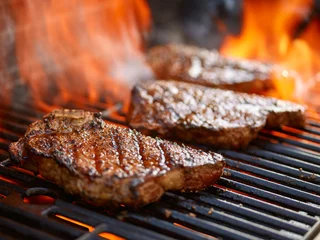 Keuken spatwand met foto steaks grillen op vlammende grill en geschoten met selectieve focus © Joshua Resnick