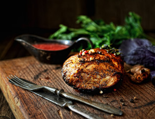 uicy grilled piece of meat on a cutting board, basil, parsley, spices
