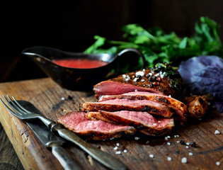 uicy grilled piece of meat on a cutting board, basil, parsley, spices
