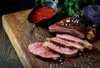 uicy grilled piece of meat on a cutting board, basil, parsley, spices
