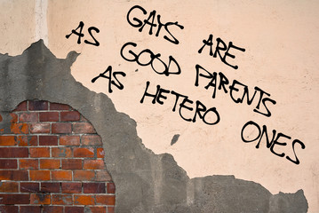 Handwritten graffiti Gays Are As Good Parents As Hetero Ones sprayed on the wall, anarchist...