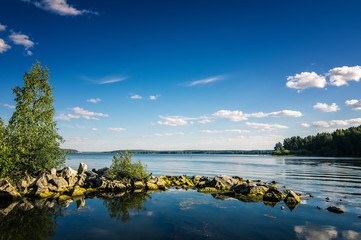летний пейзаж уральского озера с камнями в воде,...