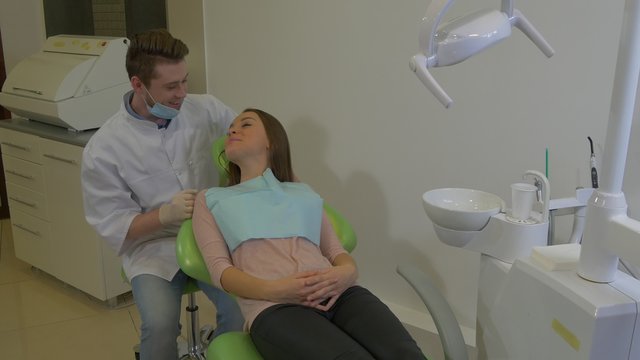 Dentist is Talking to a Client Friendly Young Woman is Smiling Lying on a Chair Young Blond Doctor and a Patient Dental Clinic Examination of a Teeth