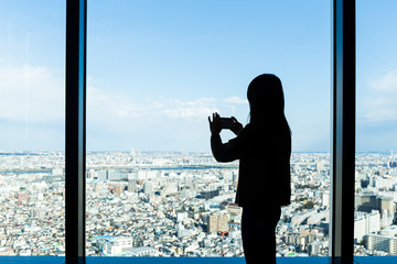 Fototapeta premium Silhouette of woman taking photo on Tokyo city