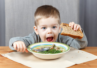 Funny little kid with plate of soup for dinner © Vanoa2
