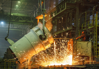 steel worker takes a sample of hot metal