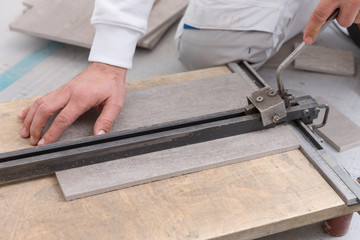 Ein Fliesenleger schneidet eine Fliese mit einem Fliesenschneider