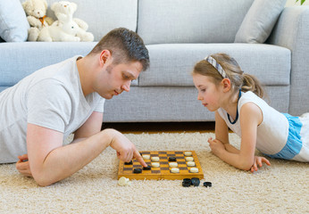 Little girl and her father playing checkers.