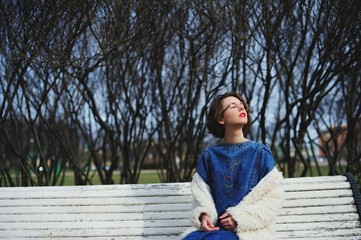 girl sitting on a bench face exposed to the sun