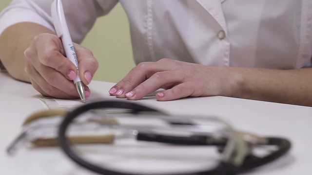 Doctor in the office records in the patient's card