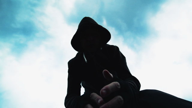 Violent attack, unrecognizable hooded male criminal kicking and punching victim on the street, victim's pov while laying on the ground.