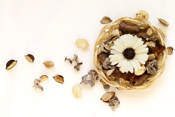 dried flowers and leaves in wicker basket on white background