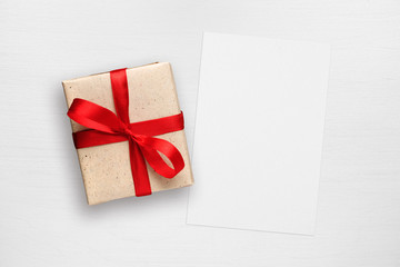 Gift box and greeting card on white wooden table