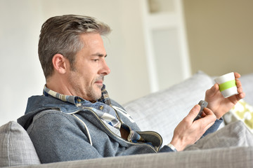 Fototapeta premium Man relaxing in sofa, using smartphone