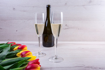 photo of two champagnes glasses and bottle on white wooden table with copy space.