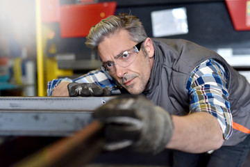 Metalworker checking piece of iron in workshop