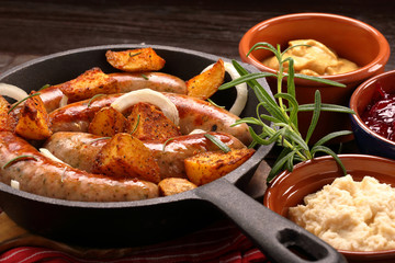 White sausages with potatoes baked in a frying pan
