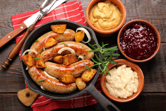 White sausages with potatoes baked in a frying pan