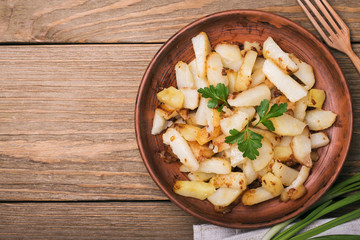 Fried potatoes with parsley and onion in an earthenware dish
