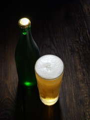 Beer in glass and bottle on a wooden background