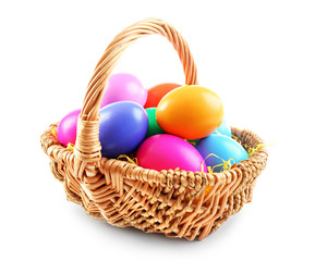 Multicoloured Easter eggs in wicker basket isolated on white