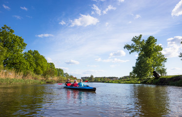 Young people are kayaking on a river in beautiful nature. Summer sunny day 
