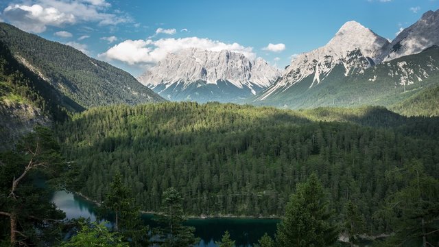 Zugspitze mountains with flowing clouds over the forest. Blindsee. Timelapse HD