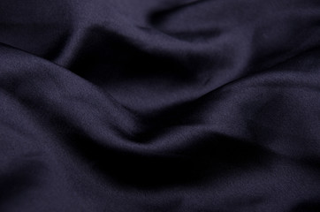 Fototapeta na wymiar Black silk as a wavy black background (shallow DOF, selective focus on the curves)