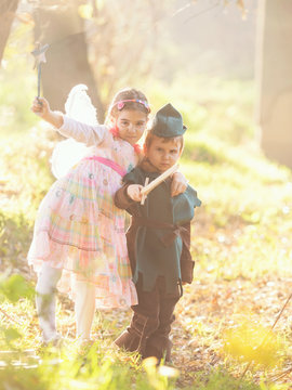 Cute little children dressed up as a knight and a fairy playing in the woods