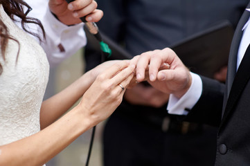 bride wears a wedding ring on finger of groom