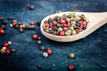 mixture of peppers on spoon in wooden background.