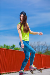 Teen girl skater riding skateboard on street.