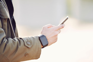 Men's hand wearing a smart watch and holding mobile phone