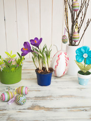 Ostertisch mit Frühlingsblumen und Eiern in den Pastell-Frühlingsfarben auf einem beigen Holzhintergrund