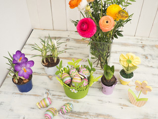 Schöne Oster-Tischdekoration mit bemalten Eiern, einen Strauß Blumen und selbstgemachten Stoffblumen in Pastellfarben 