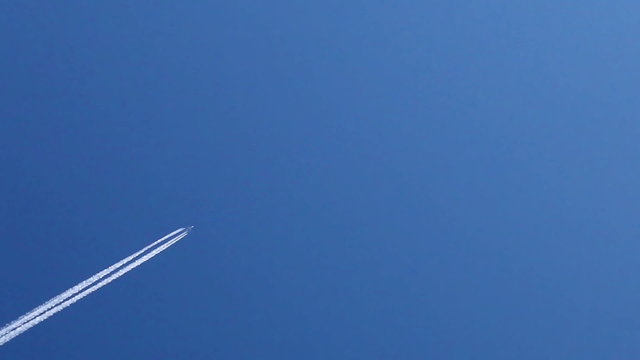 Airplane trails across clear blue sky