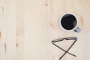 Coffee cup being raised and eyeglasses. Top view.