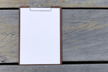 Blank paper on paper clipboard with space on wood background
