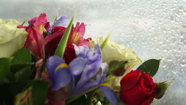 Drops of water falling on beautiful bouquet of roses, iris and alstroemeria.