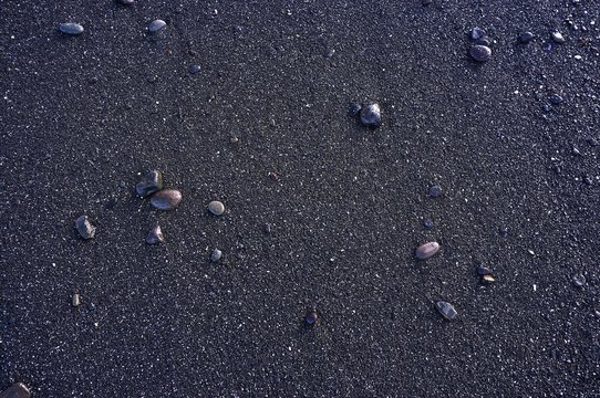 wet pebbles on black beach sand background