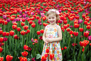 Girl is smiling on a flower glade of tulips