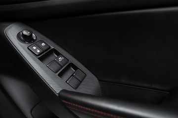 Obraz na płótnie Canvas Car interior details of door handle with windows controls and adjustments. Car window controls and details